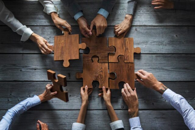 https://doradcy365.pl/wp-content/uploads/2022/12/business-people-team-sitting-around-meeting-table-and-assembling-wooden-jigsaw-puzzle-pieces-unity-cooperation-ideas-concept-min-640x427.jpg